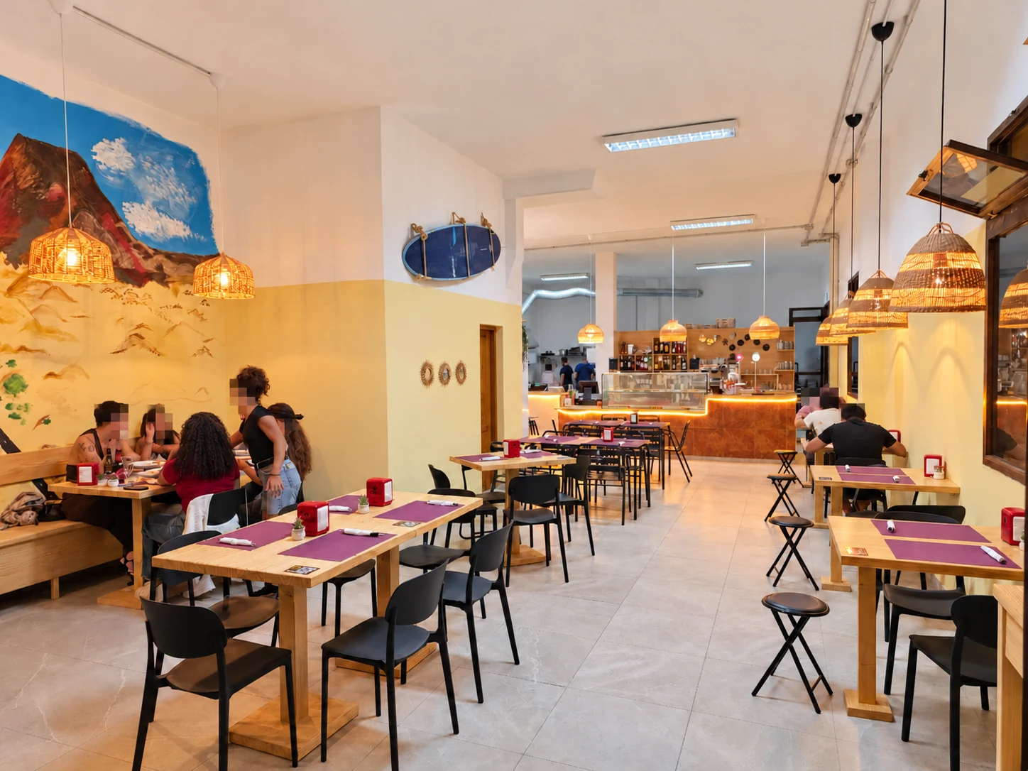 Salón de La Diana, con mesas de madera y lámparas de fibras naturales; caras pixeladas